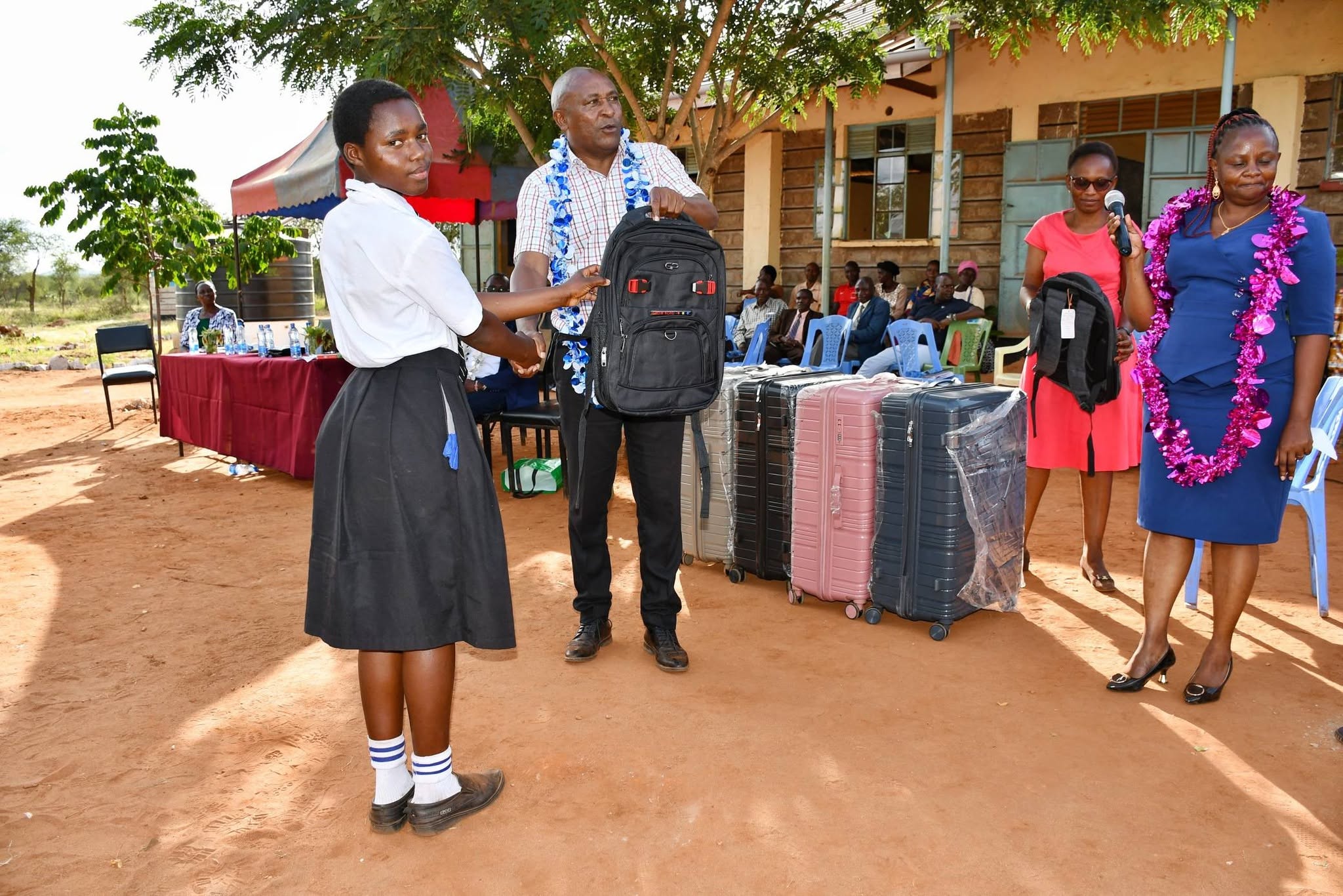 A learner receives a school bag from a county official during a bursary hand-over