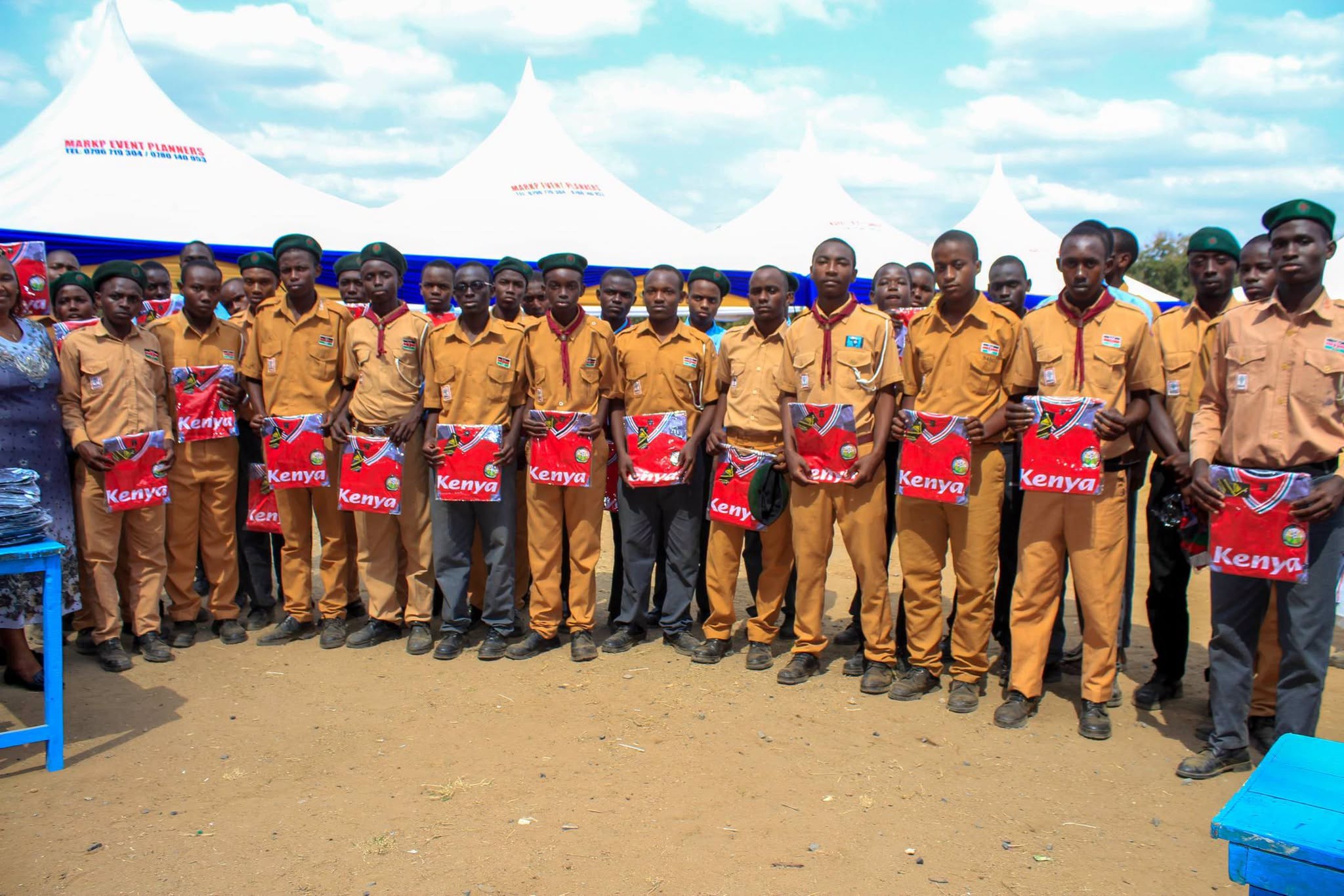 Secondary school scouts hold new Kenya team jerseys in front of event tents